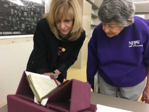 From left, president Viv Sade and secretary Marion Garmel examined the first log book from 1913. (Photo by Elizabeth Granger)